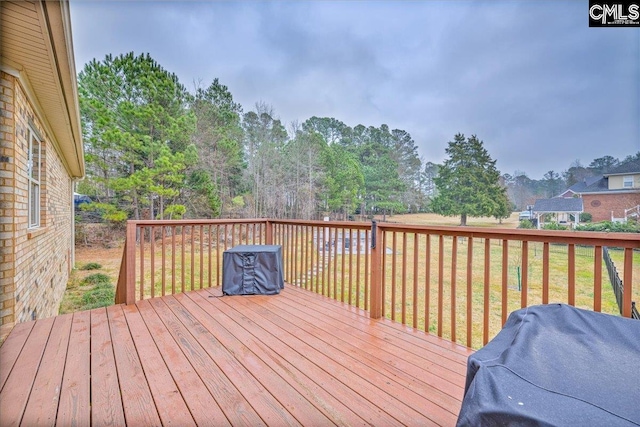 wooden deck featuring area for grilling and a yard