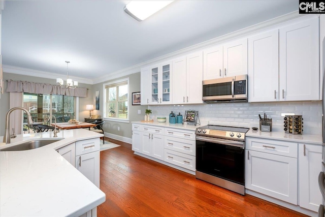 kitchen featuring decorative light fixtures, white cabinetry, sink, ornamental molding, and stainless steel appliances