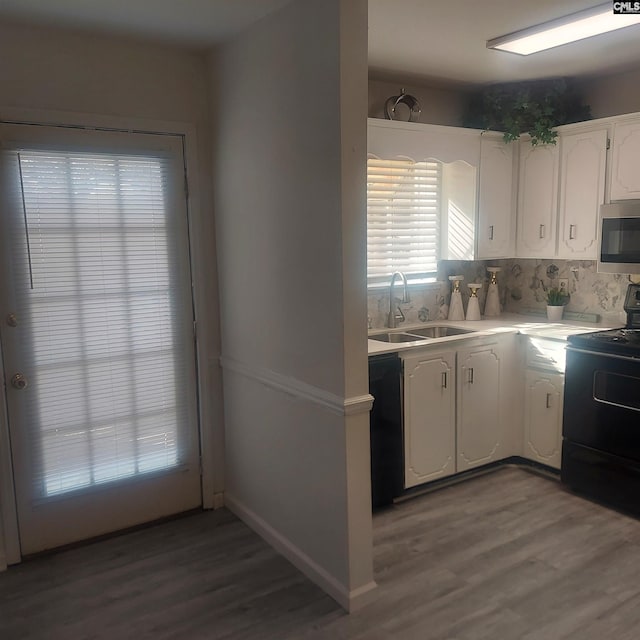 kitchen with sink, hardwood / wood-style flooring, black appliances, and white cabinets