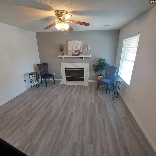 sitting room featuring ceiling fan, wood-type flooring, and a textured ceiling