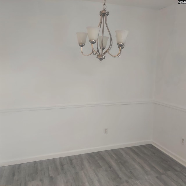 spare room with hardwood / wood-style floors and a notable chandelier