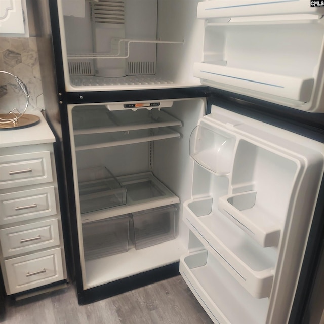 details with fridge, hardwood / wood-style floors, white cabinets, and backsplash