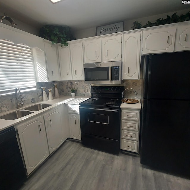 kitchen with sink, wood-type flooring, black appliances, white cabinets, and backsplash