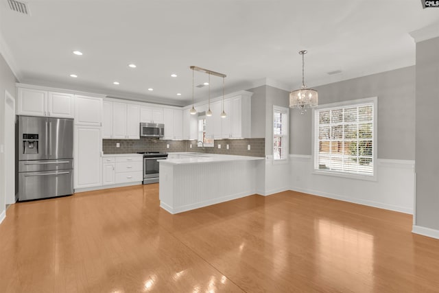 kitchen with white cabinetry, hanging light fixtures, and stainless steel appliances