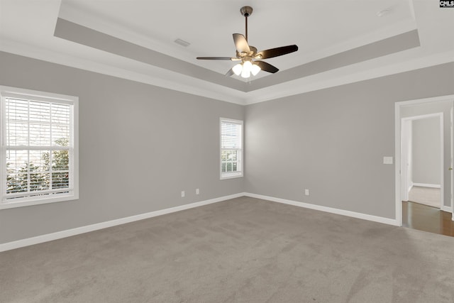 carpeted spare room with crown molding, a tray ceiling, and ceiling fan