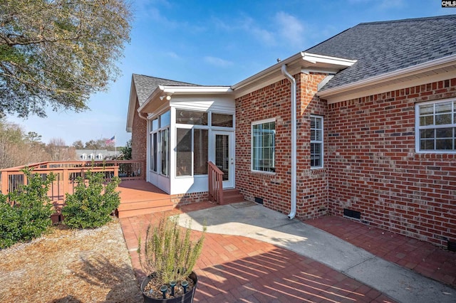 rear view of house with a wooden deck, a sunroom, and a patio