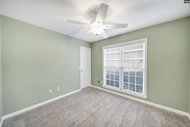 carpeted spare room with a textured ceiling and ceiling fan