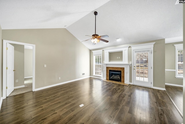 unfurnished living room featuring a tiled fireplace, ceiling fan, lofted ceiling, and dark hardwood / wood-style flooring