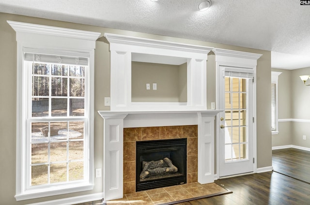 unfurnished living room featuring a tile fireplace, hardwood / wood-style floors, and a textured ceiling