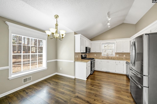 kitchen featuring decorative light fixtures, white cabinetry, sink, stainless steel appliances, and light stone countertops