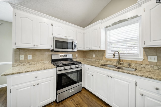 kitchen with white cabinetry, sink, stainless steel appliances, and lofted ceiling