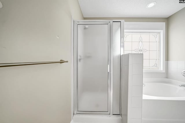 bathroom featuring shower with separate bathtub and a textured ceiling