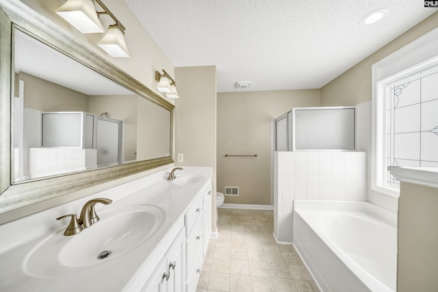 full bathroom featuring independent shower and bath, vanity, a textured ceiling, and toilet