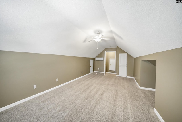 bonus room featuring vaulted ceiling, light carpet, a textured ceiling, a wall unit AC, and ceiling fan