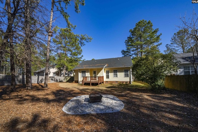 back of property with an outdoor fire pit and a deck