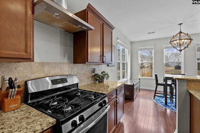 kitchen featuring light stone countertops, dark wood-type flooring, stainless steel gas range, and wall chimney exhaust hood