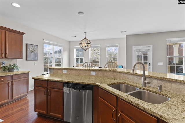 kitchen featuring pendant lighting, sink, light stone counters, a healthy amount of sunlight, and stainless steel dishwasher