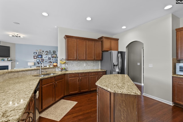 kitchen featuring stainless steel appliances, light stone countertops, sink, and decorative backsplash