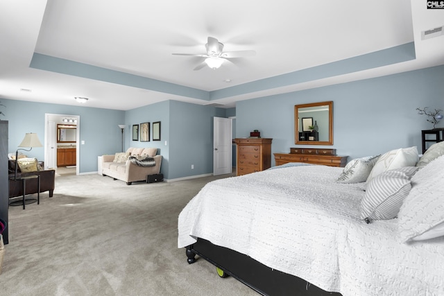 bedroom featuring carpet flooring, connected bathroom, ceiling fan, and a tray ceiling