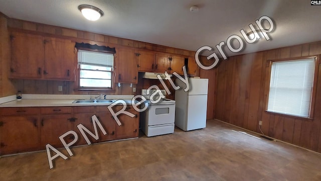 kitchen with white appliances, sink, and wood walls