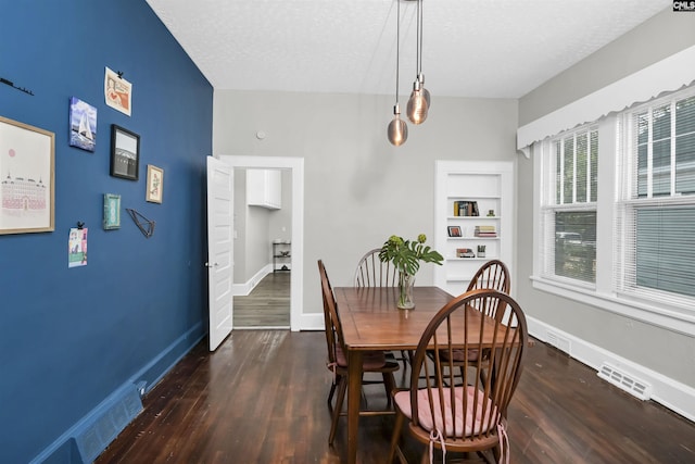 dining room featuring dark wood-type flooring, a textured ceiling, and built in shelves