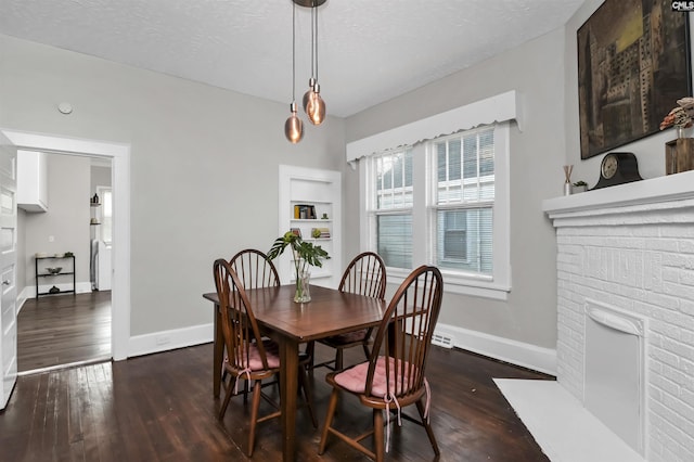 dining room with a fireplace, dark hardwood / wood-style flooring, a textured ceiling, and built in features