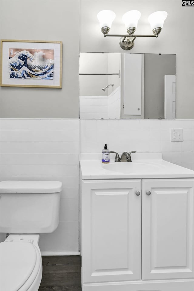 bathroom with hardwood / wood-style flooring, vanity, tile walls, and toilet