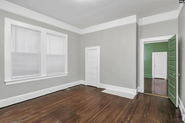 empty room featuring crown molding and dark wood-type flooring