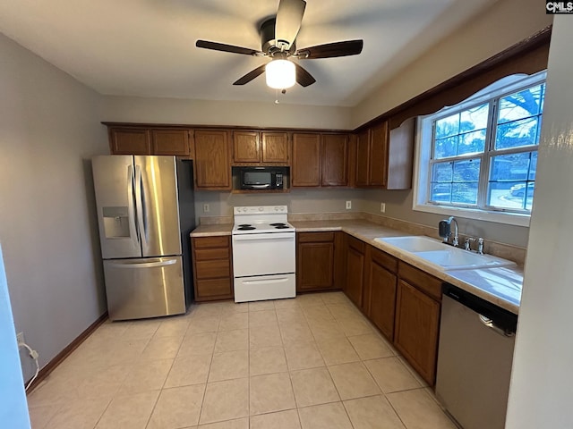 kitchen featuring light tile patterned flooring, appliances with stainless steel finishes, sink, and ceiling fan