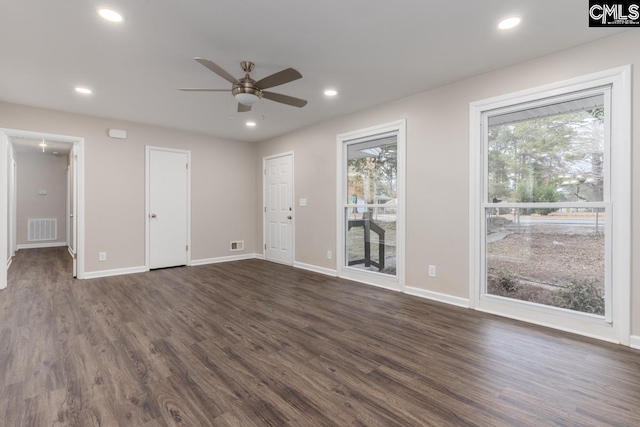 empty room featuring plenty of natural light, dark hardwood / wood-style floors, and ceiling fan