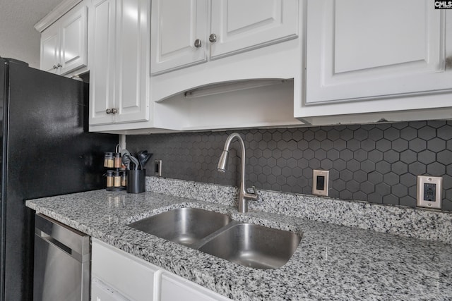 kitchen featuring sink, tasteful backsplash, light stone countertops, white cabinets, and stainless steel dishwasher