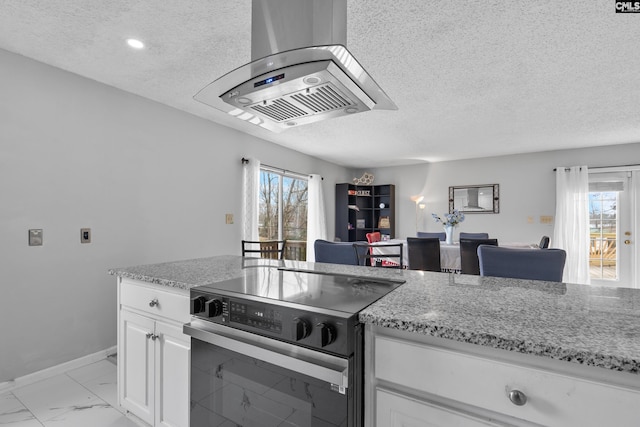 kitchen featuring white cabinets, plenty of natural light, a textured ceiling, and range with electric stovetop