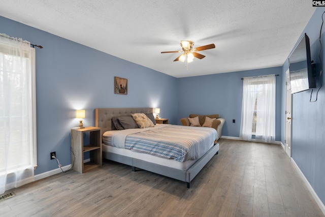 bedroom featuring ceiling fan, wood-type flooring, and a textured ceiling