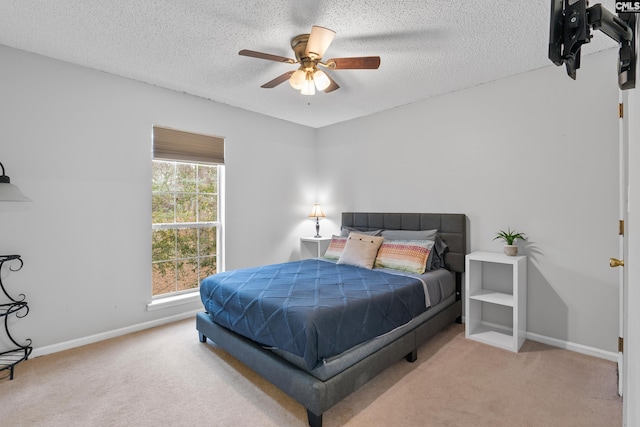 bedroom featuring ceiling fan, light colored carpet, and a textured ceiling