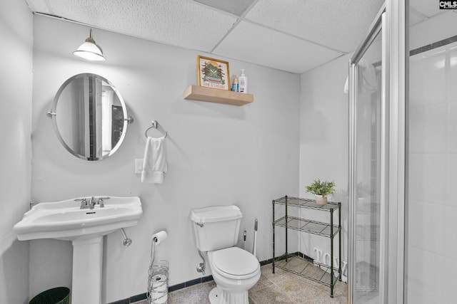 bathroom with a drop ceiling, sink, toilet, and walk in shower