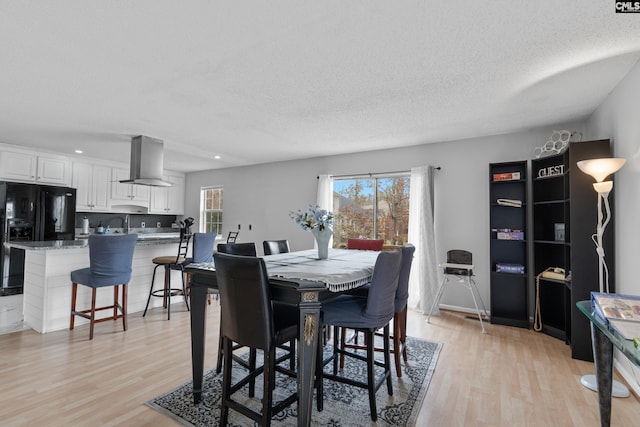 dining space featuring a textured ceiling, a healthy amount of sunlight, and light wood-type flooring