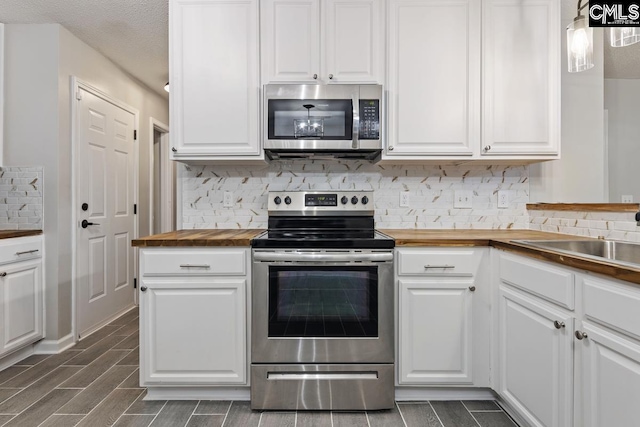 kitchen with butcher block counters, sink, tasteful backsplash, appliances with stainless steel finishes, and white cabinets