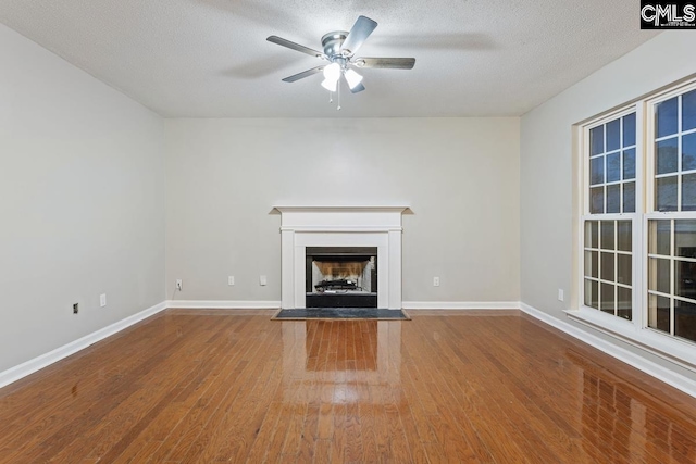 unfurnished living room featuring wood-type flooring, ceiling fan, and a textured ceiling