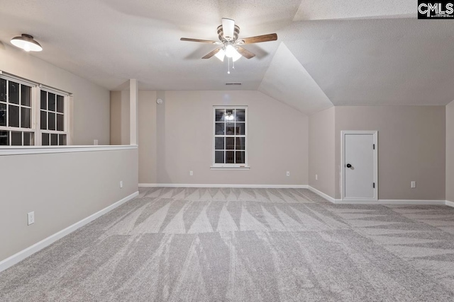 additional living space featuring ceiling fan, light colored carpet, lofted ceiling, and a textured ceiling