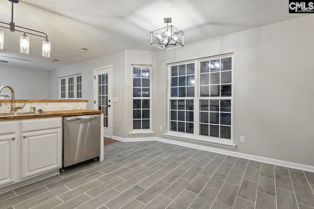 kitchen featuring sink, tasteful backsplash, decorative light fixtures, stainless steel dishwasher, and white cabinets