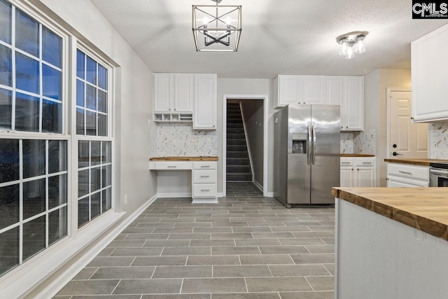 kitchen with pendant lighting, wood counters, stainless steel fridge with ice dispenser, and white cabinets