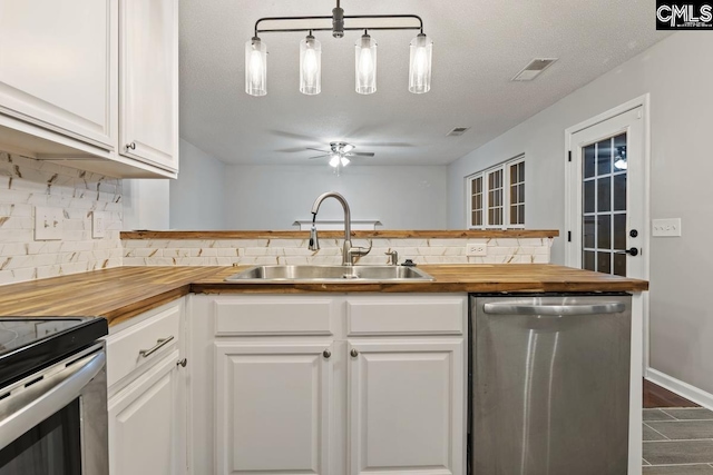 kitchen with stainless steel appliances, white cabinetry, butcher block counters, and sink