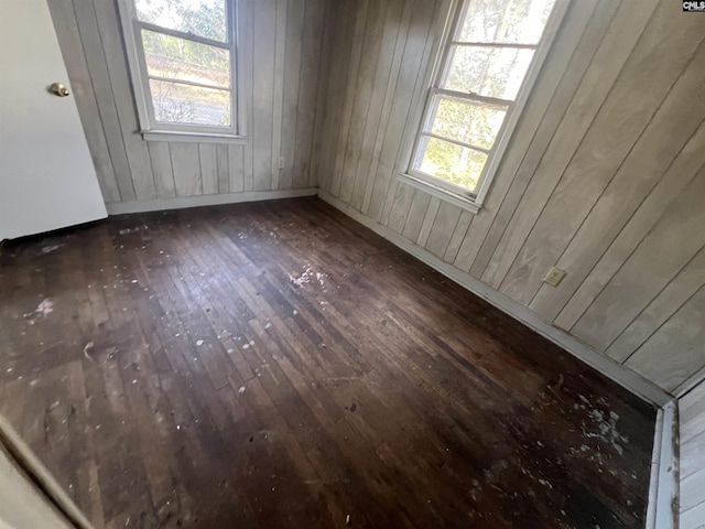 unfurnished room with dark wood-type flooring and wood walls