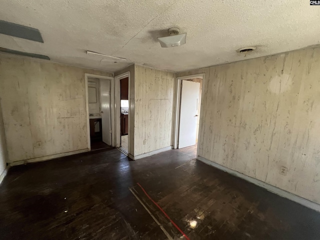 unfurnished room with dark hardwood / wood-style flooring and a textured ceiling