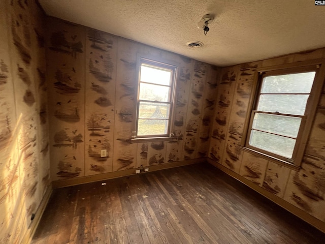 empty room with dark hardwood / wood-style floors and a textured ceiling