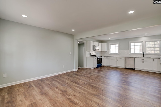 kitchen with sink, tasteful backsplash, hardwood / wood-style flooring, stainless steel appliances, and white cabinets