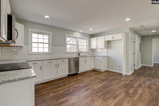 kitchen with appliances with stainless steel finishes, white cabinetry, sink, light stone countertops, and dark wood-type flooring