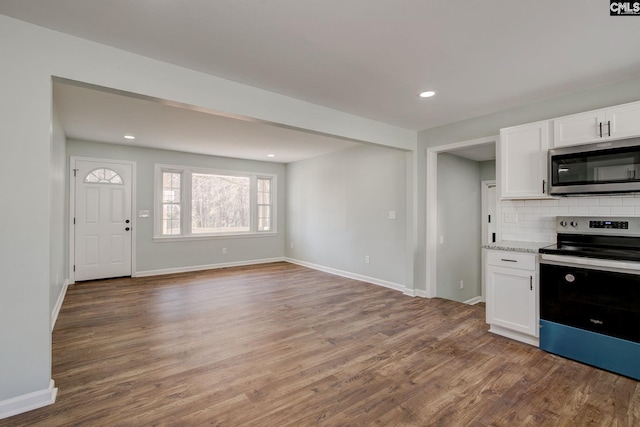 kitchen with white cabinets, backsplash, hardwood / wood-style flooring, stainless steel appliances, and light stone countertops