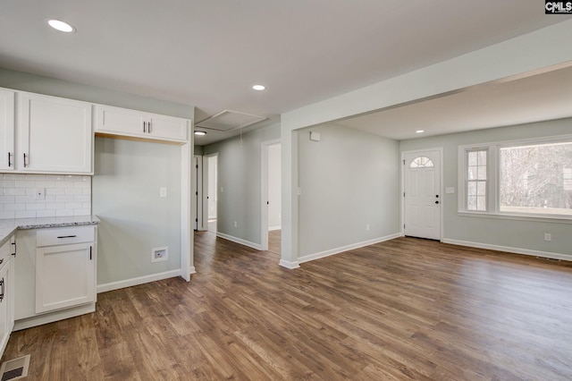 kitchen featuring hardwood / wood-style floors, white cabinets, light stone counters, and decorative backsplash