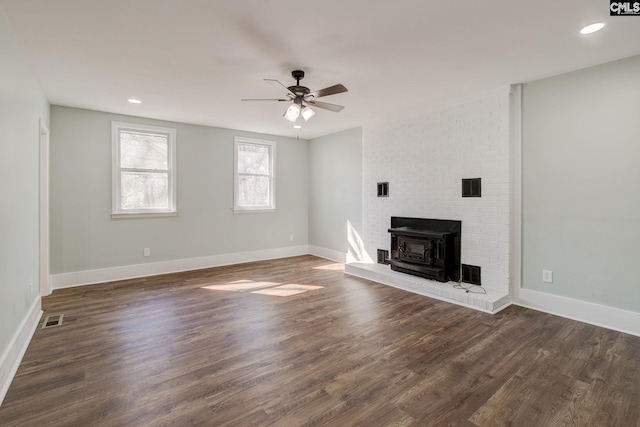 unfurnished living room with dark hardwood / wood-style floors, ceiling fan, and a wood stove